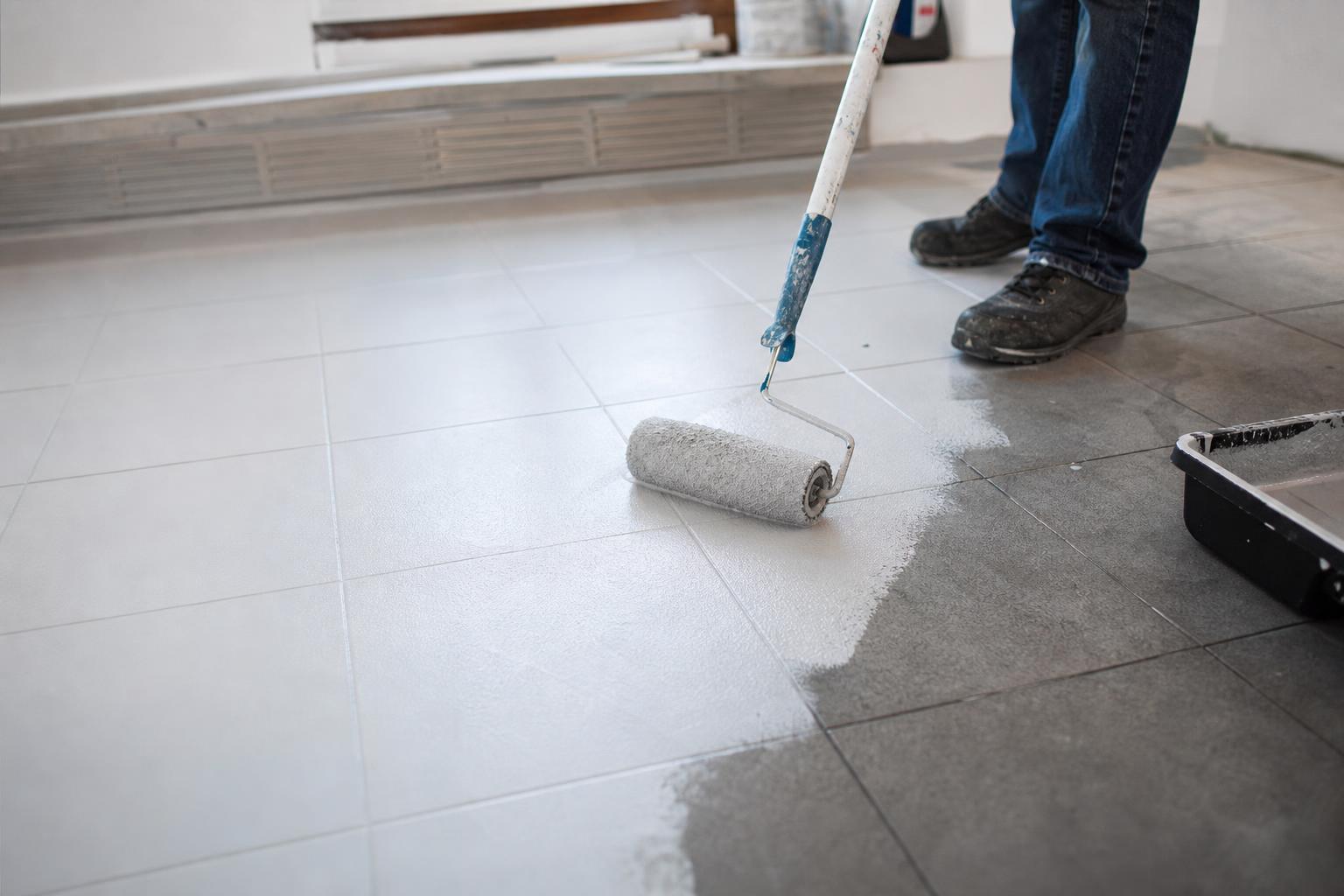 Application de la peinture au rouleau sur un carrelage de sol