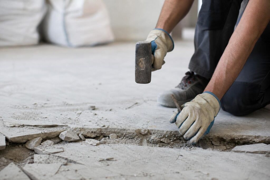 Casser une dalle en béton à la masse et au burin pendant une rénovation