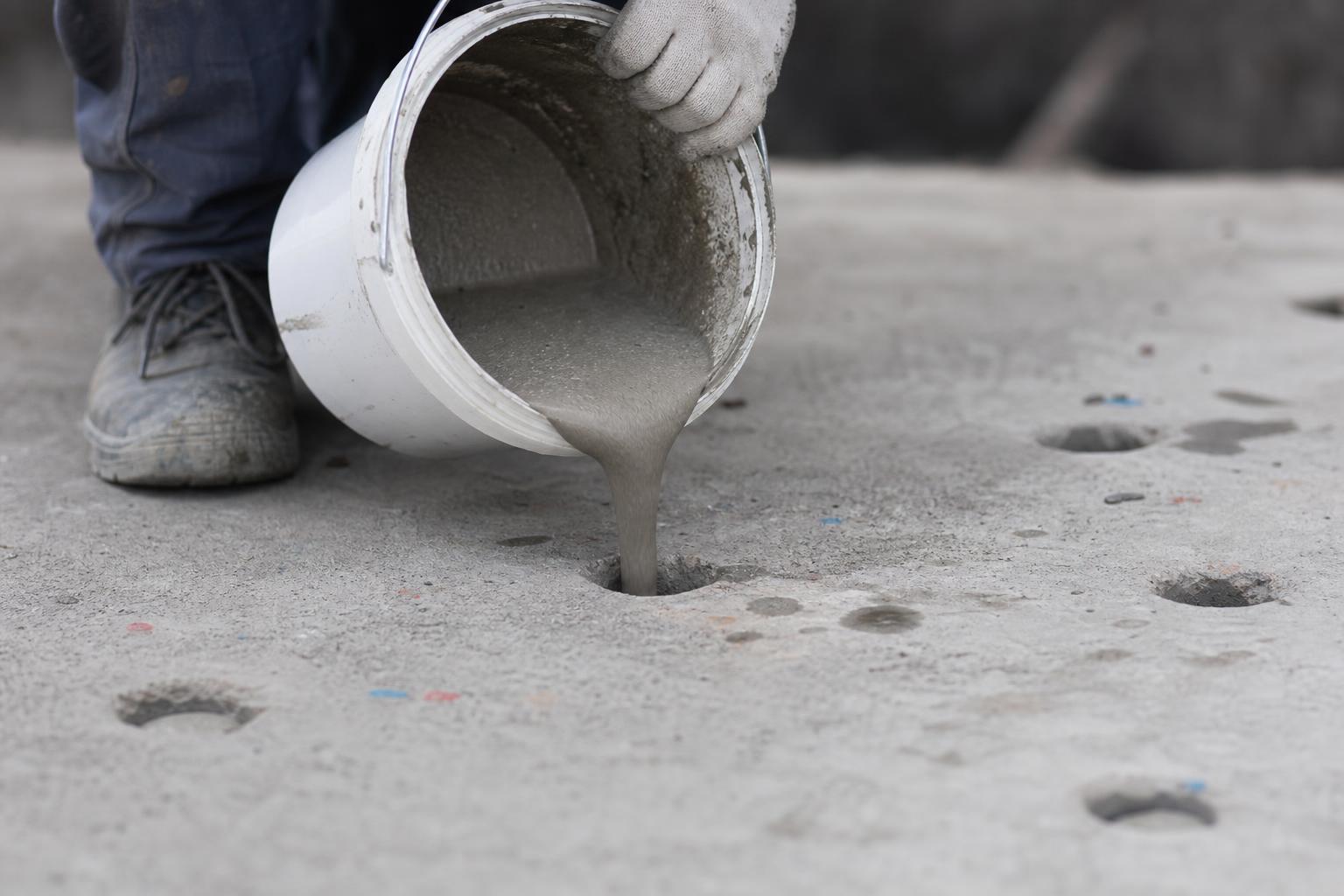 Couler du mortier expansif dans des trous percés pour casser une dalle béton