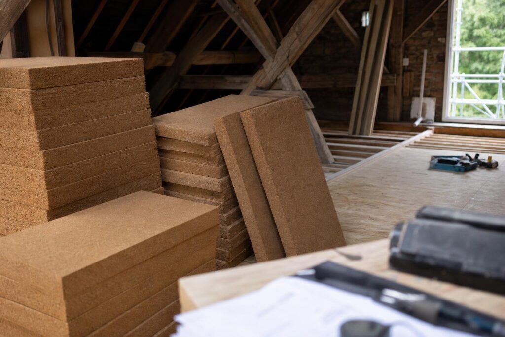 Panneaux d'isolation en fibre de bois empilés sur un chantier de rénovation sous charpente.