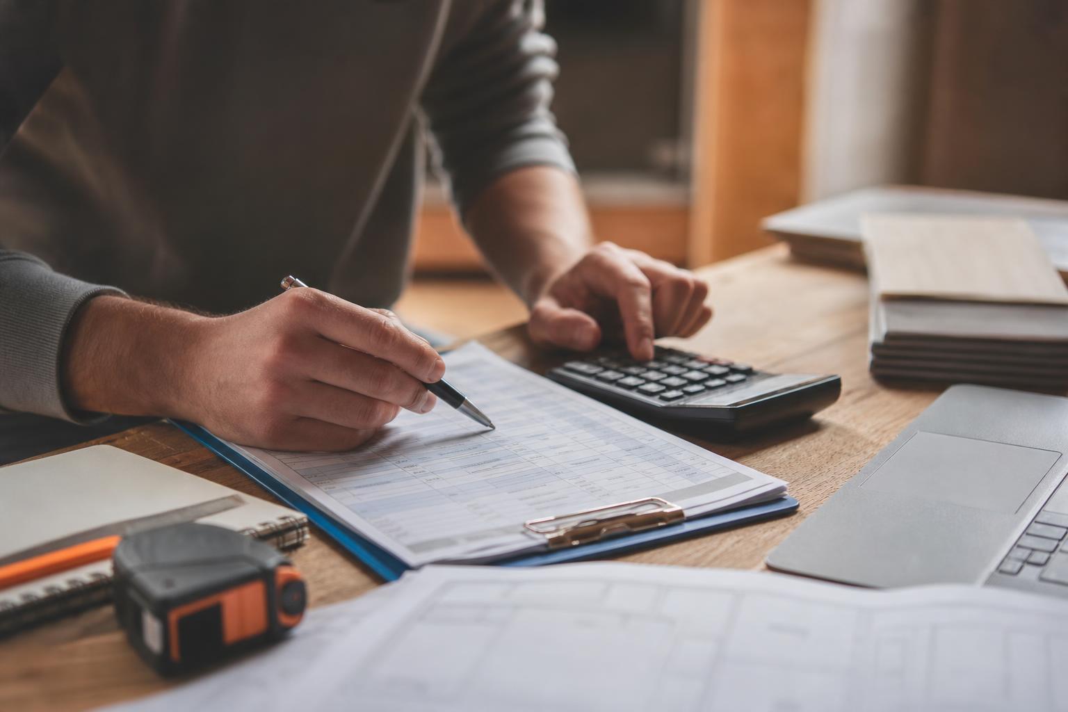 Personne examinant un devis de rénovation détaillé ligne par ligne avec un stylo et une calculatrice